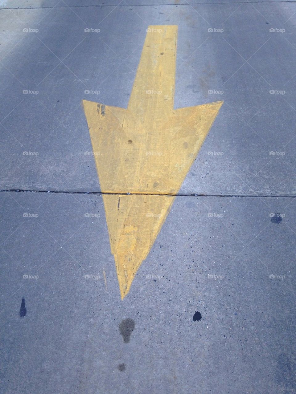 Yellow Arrow Sign on the Asphalt Road