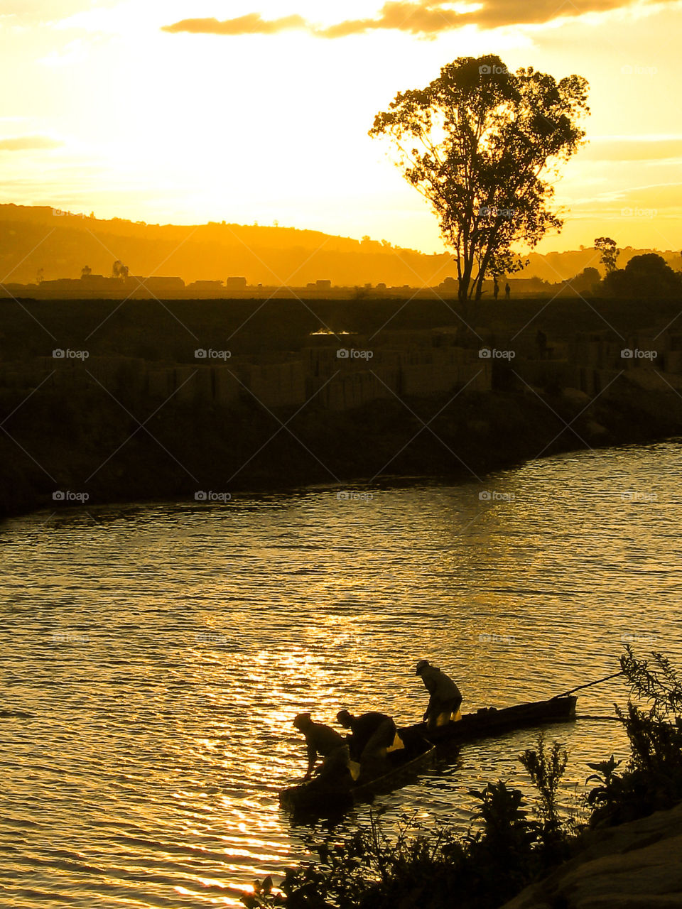 End of a work's day after making bricks on the river edge. Workers in boat on the river at sunset. Antananarivo, Madagascar
, Africa