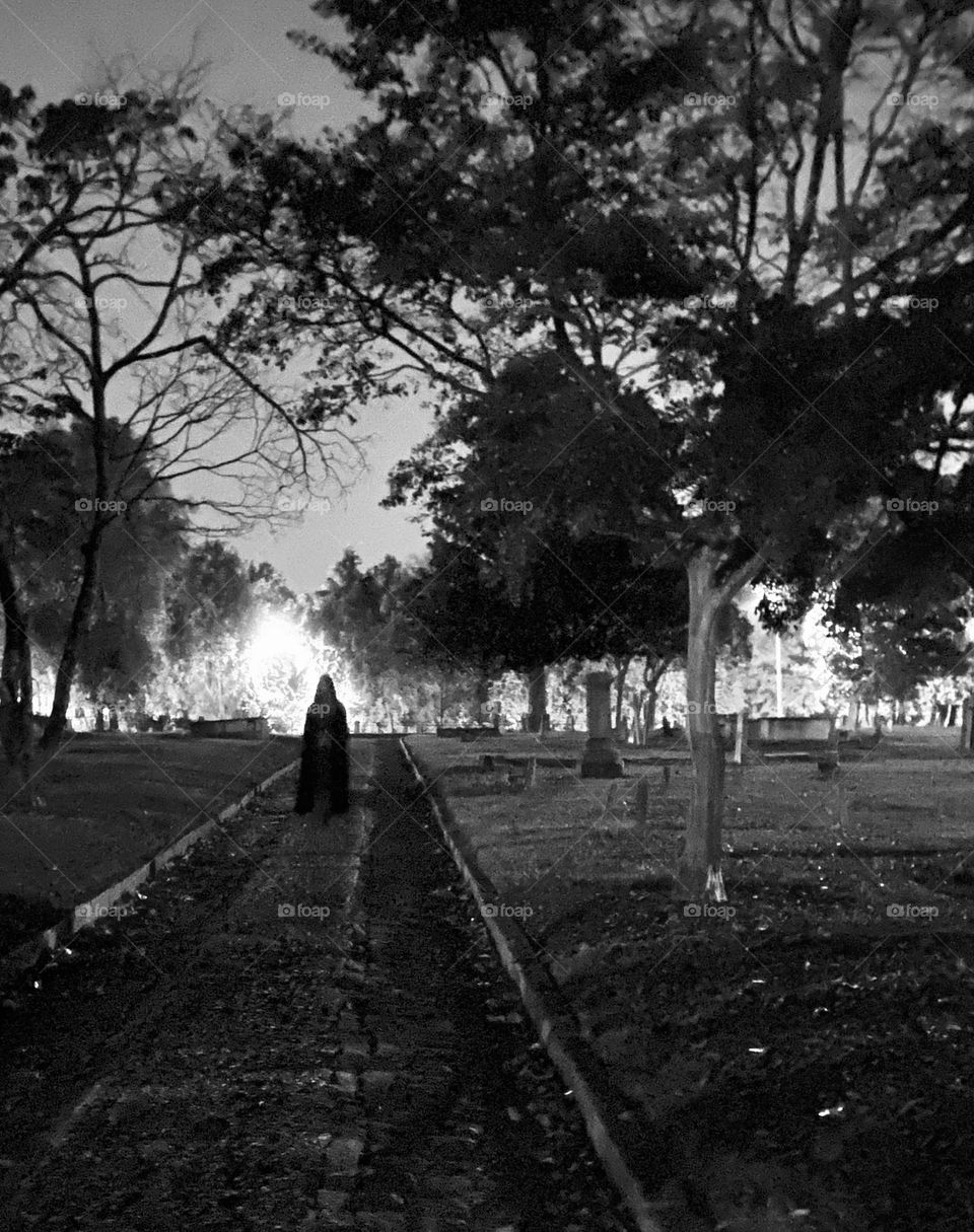 Shrouded figure in a graveyard at night , B&W 