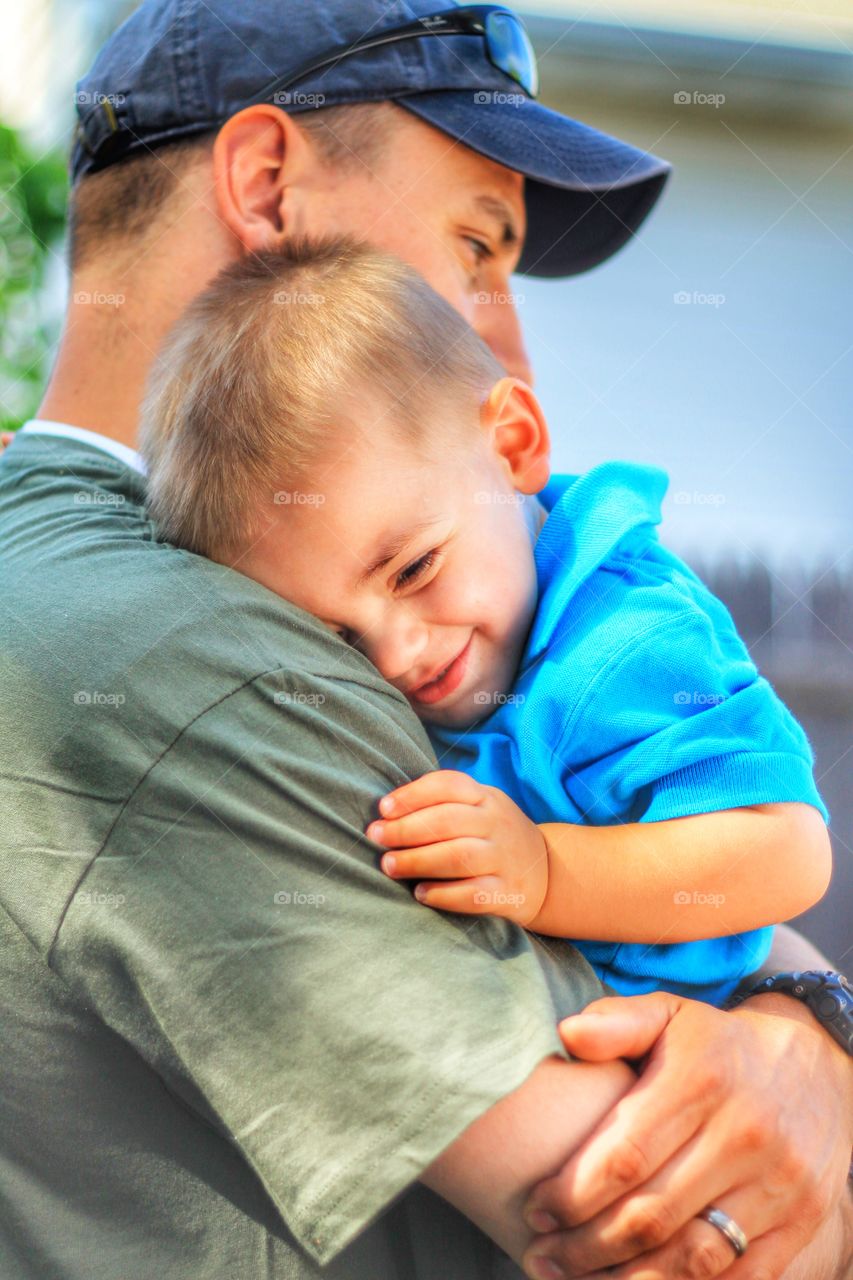 Smiling boy leaning on his father shoulder