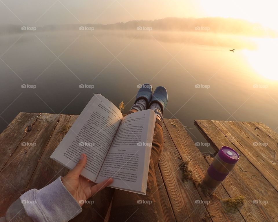 Reading a book on the river enjoying sunset and wild nature. 