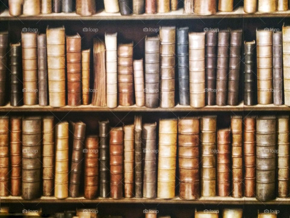 Shelves full of dusty old and antique books in a dark and gloomy library.