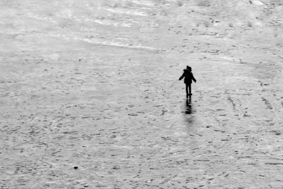 Black and white photo of the silhouette of a little girl dancing on a frozen pond