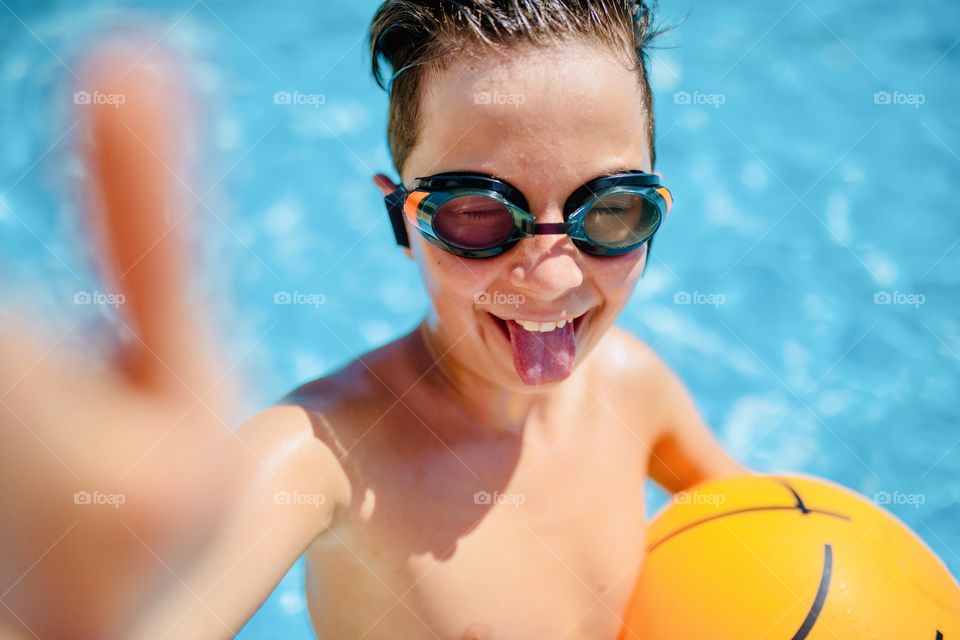 boy makes funny selfie in the pool