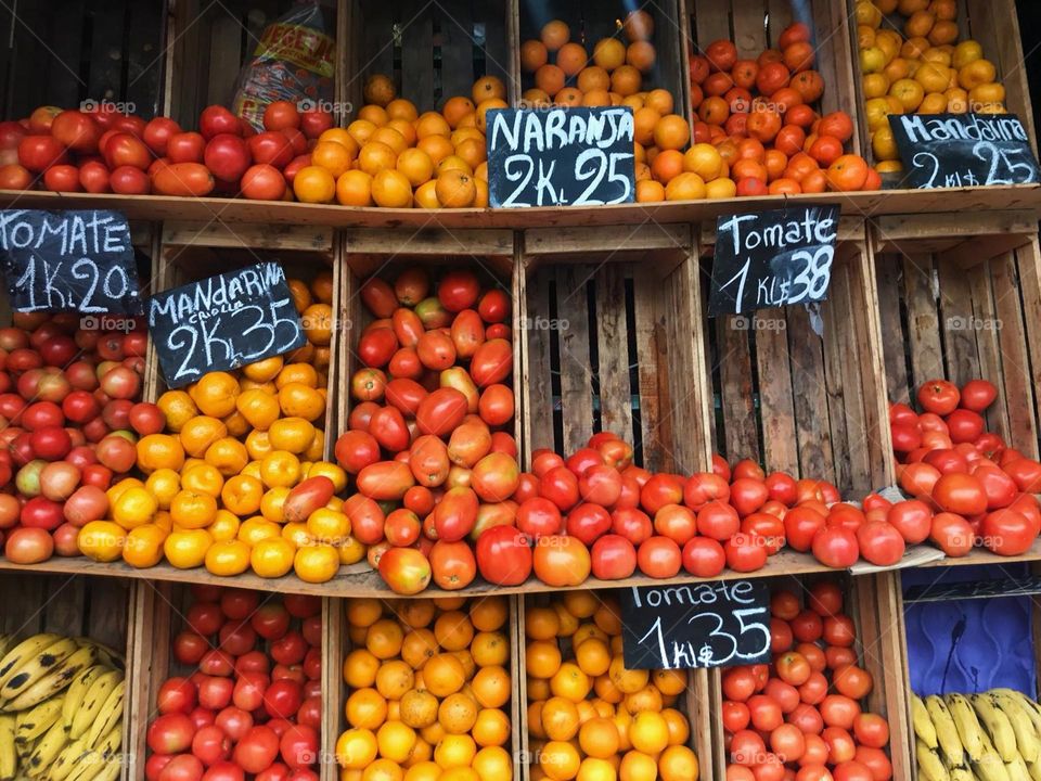 Tomatoes, oranges and mandarines for sales with blackboard price tags on a fruit and vegetables store stand in Buenos Aires, Argentina