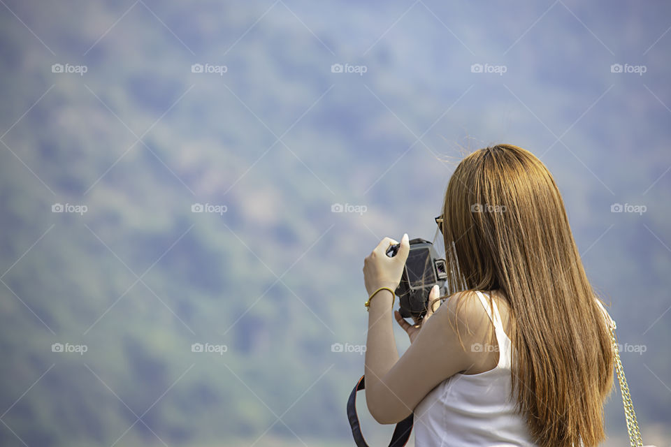 Hand woman holding the camera Background blurry tree  on mountain.