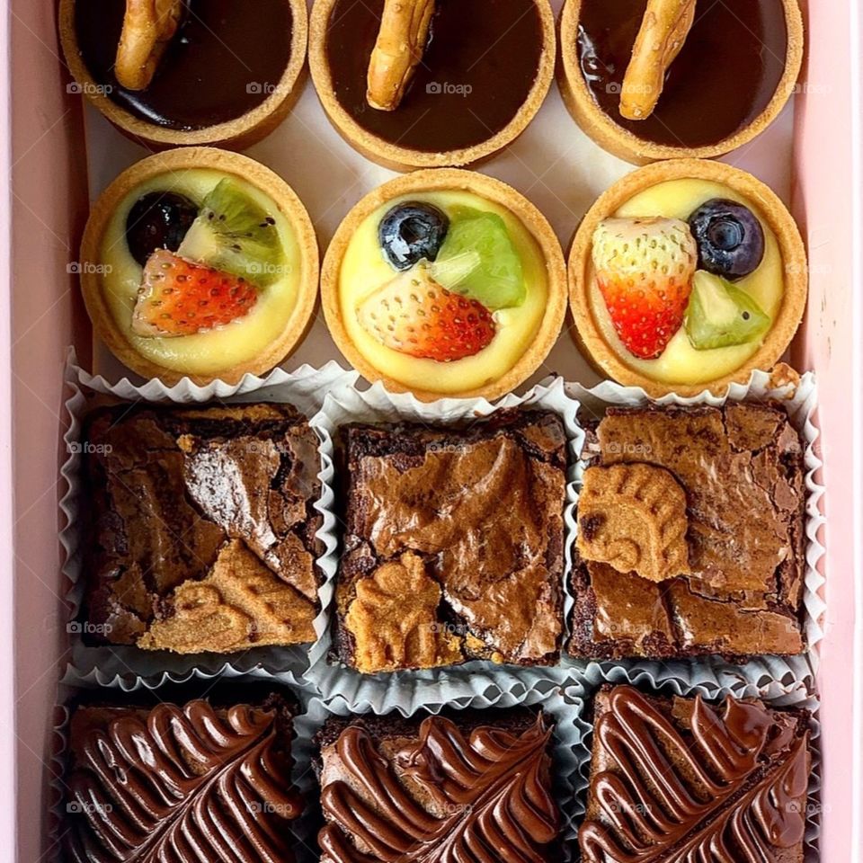 Bake box of brownies and fruit tarts nicely packed in a pink box 
