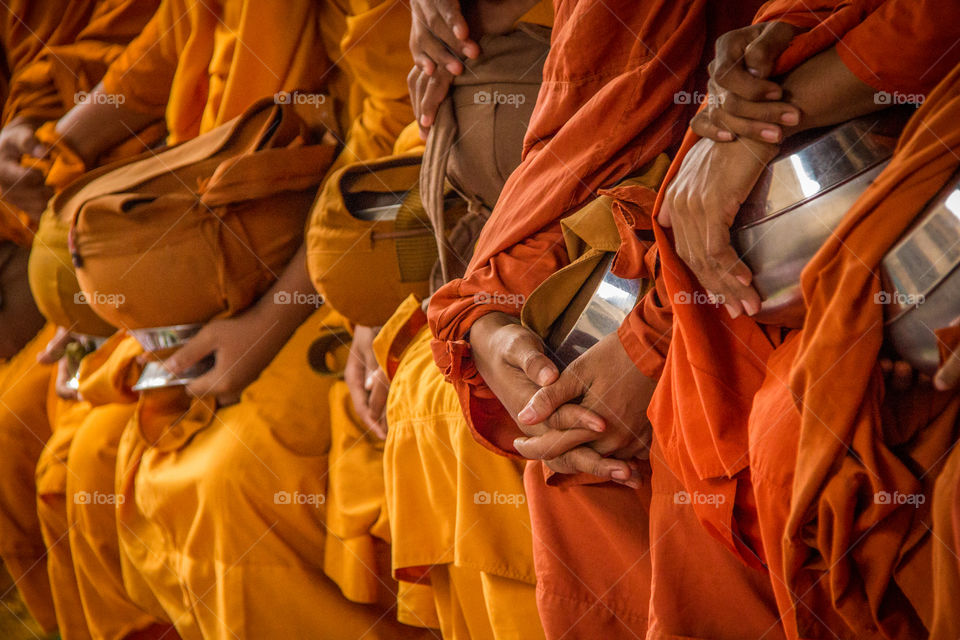 The glorious colors of monks robes as they rest their hands on their alms bowls