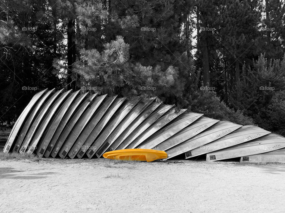 Yellow kayak sitting against gray metal boats in Hume Lake Kings Canyon national Park Vibrant yellow against the contrast of black and white