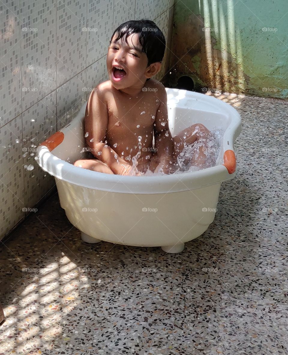 happy kid enjoying his bath in tub in summer