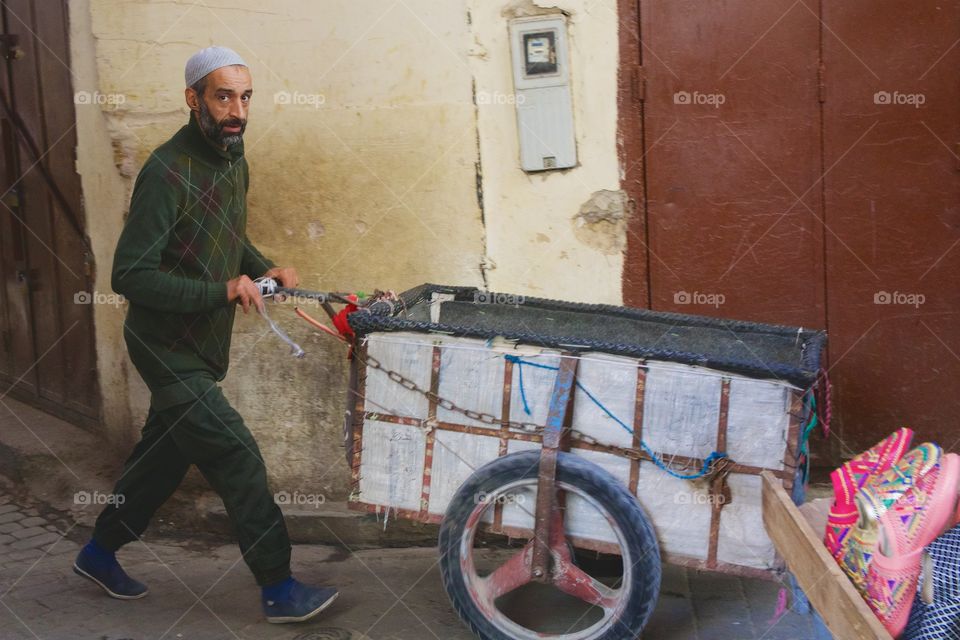 A man pushing a cart in an alley way  in Fez el Bali, Medina, Morocco, 