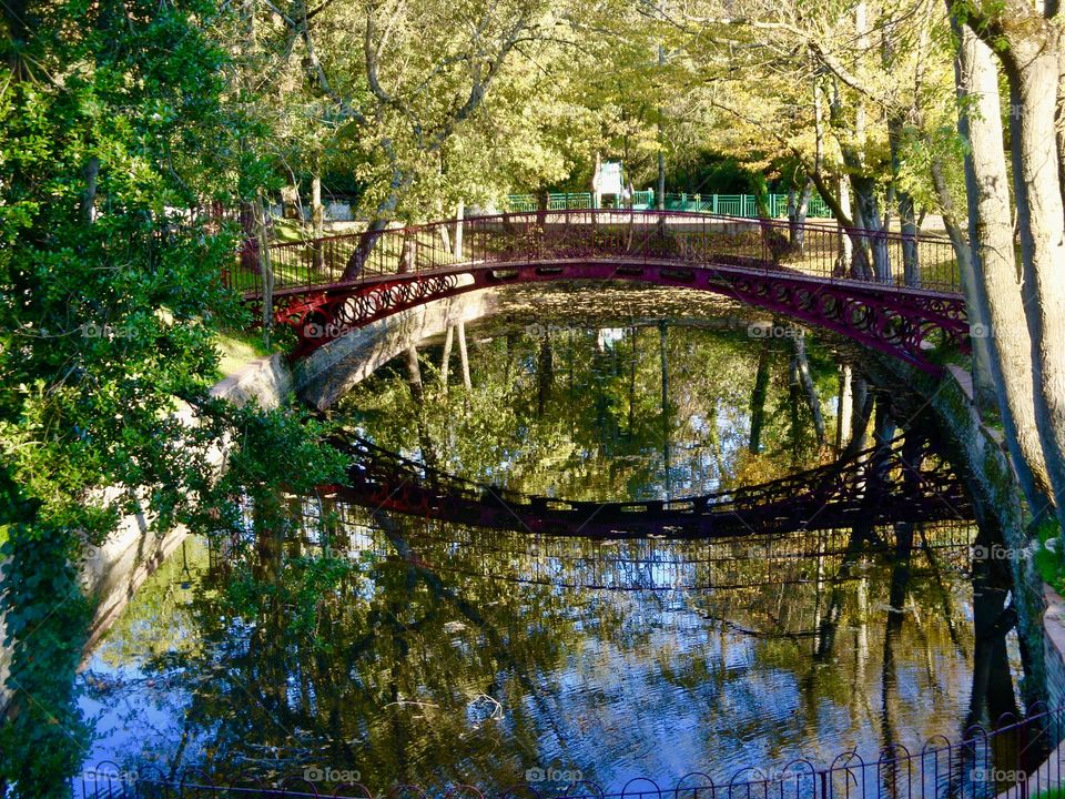 Bridge over the pond with trees reflecting 