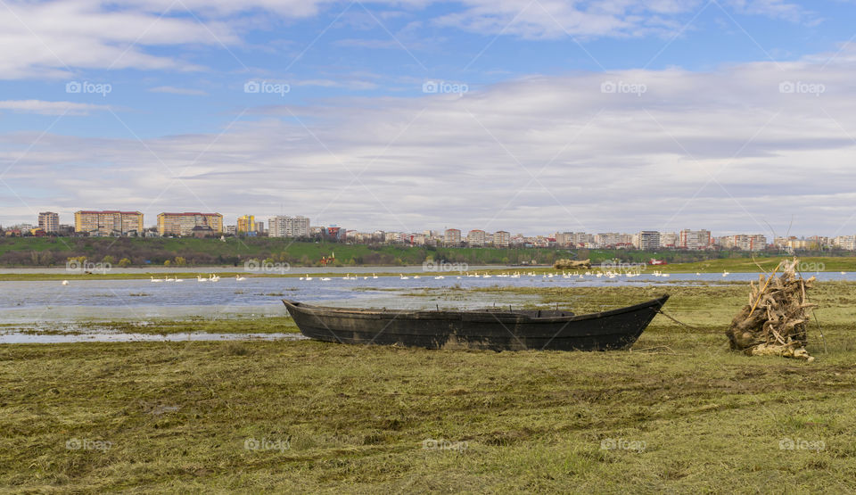 Small fishing boat.Wood boat on green grass on city background