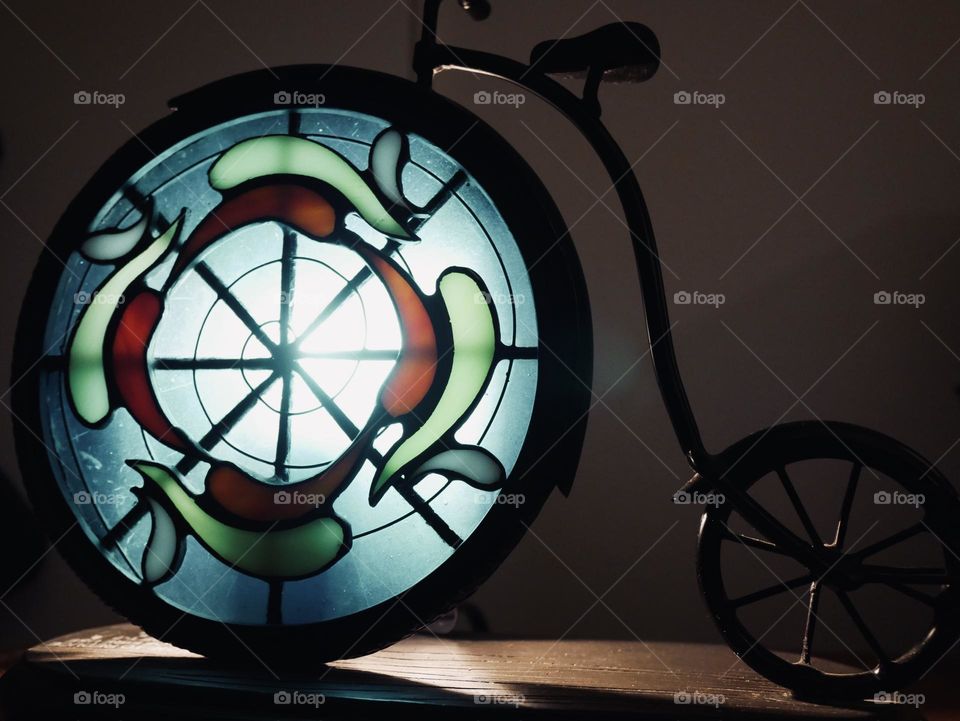 Stained glass bicycle lamp. Cool, dramatic tones, and shadows. 