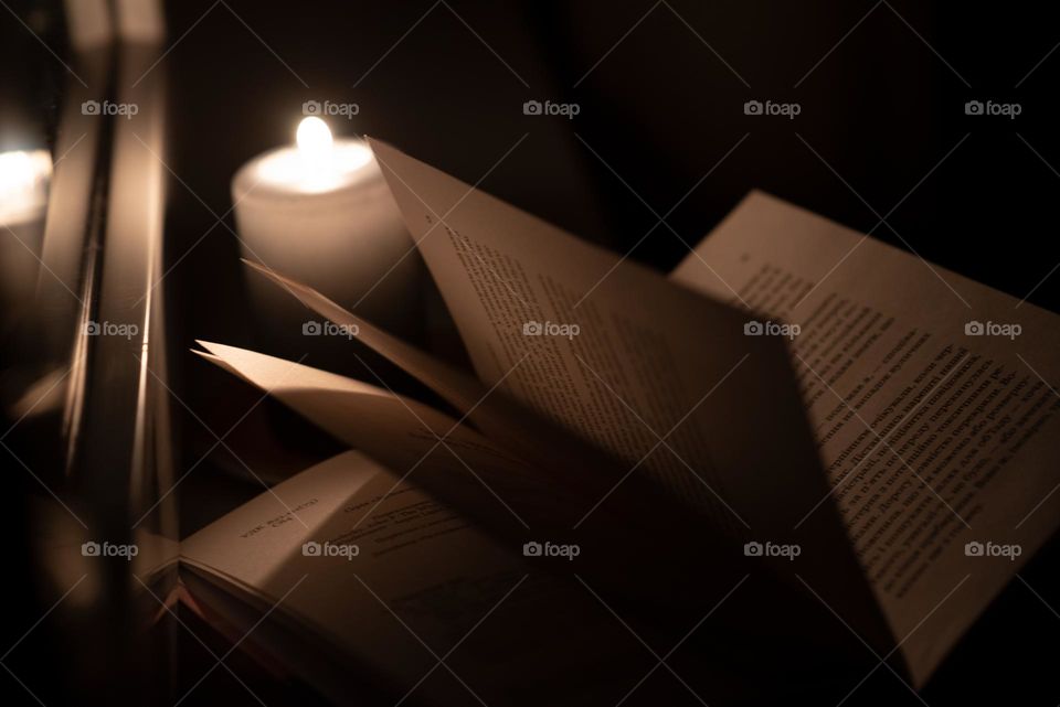 Reading a book at night over a candle by the window