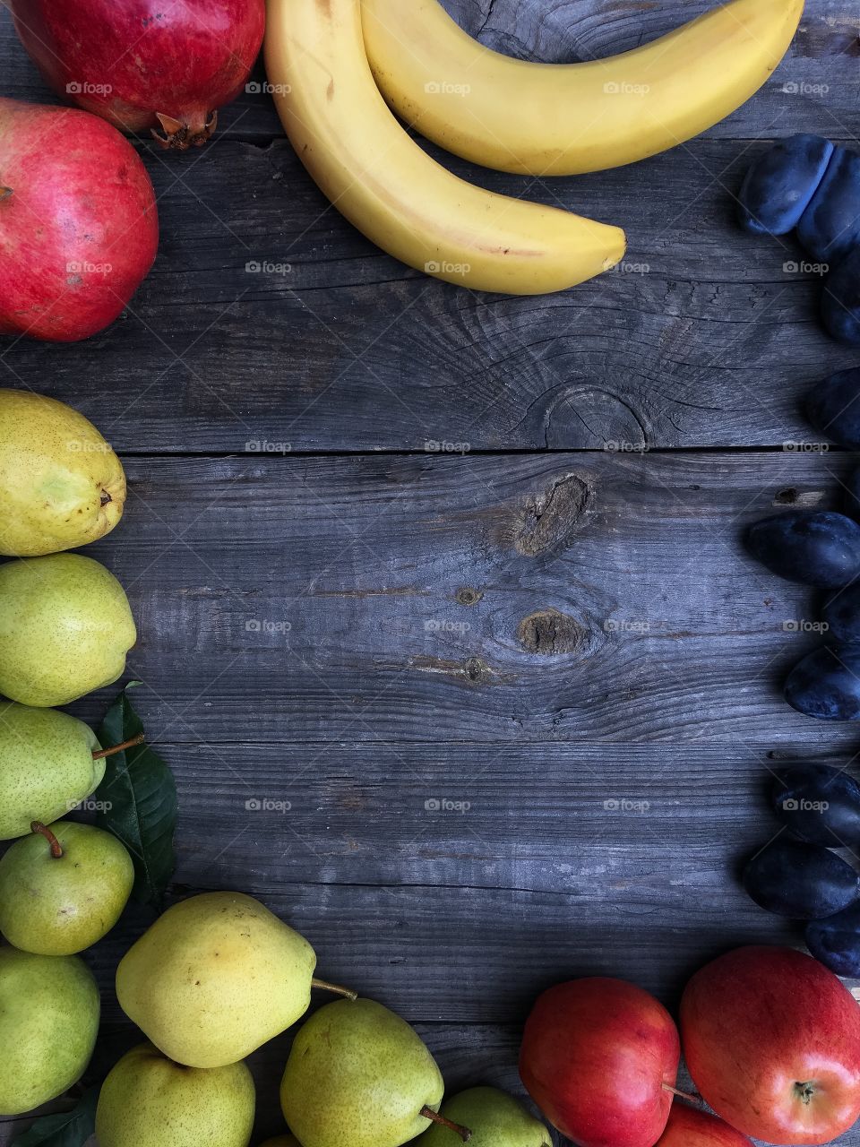 ripe fruit on a black wooden background: pear, apple, banana, pomegranate, plum