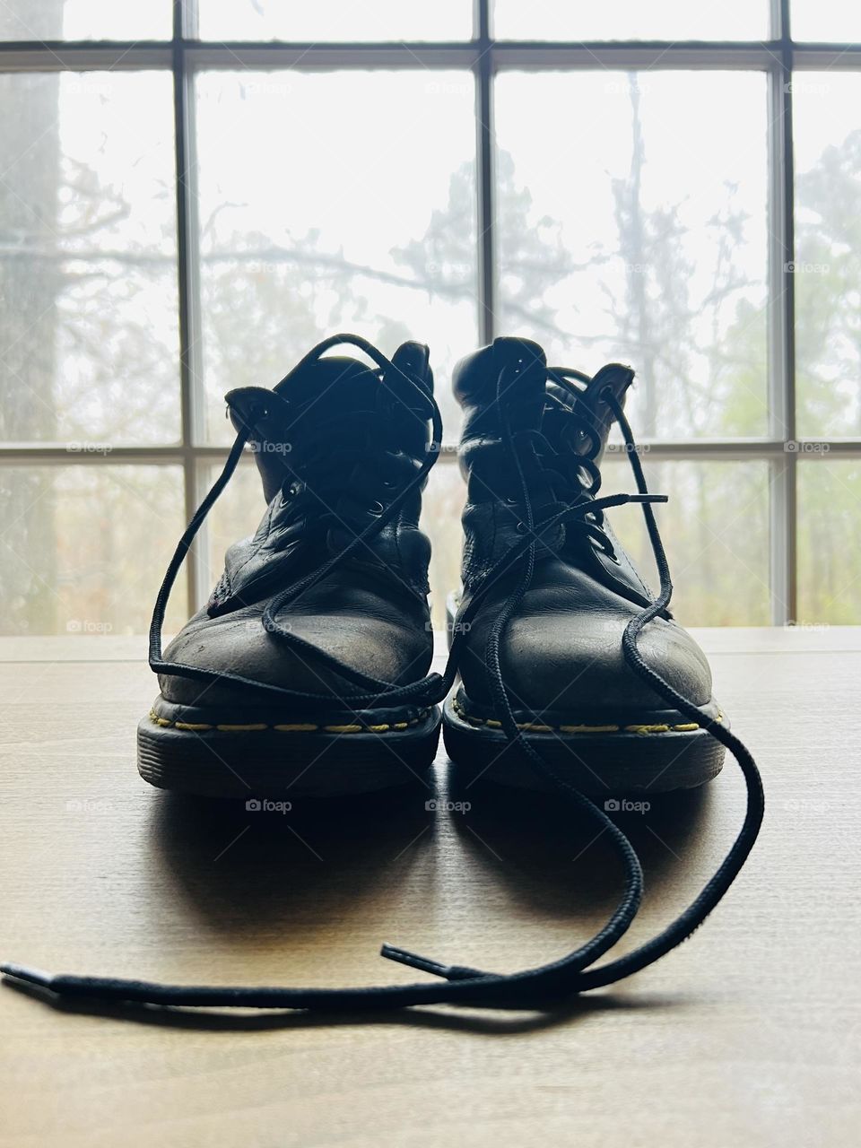 Closeup pair of worn classic Doc Marten boots backlit by window