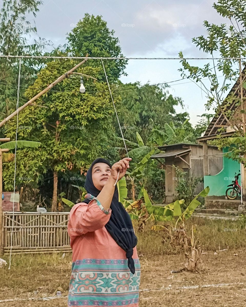 Portrait of a young mother pulling a rope hanging from a loma to celebrate Indonesia's independence day