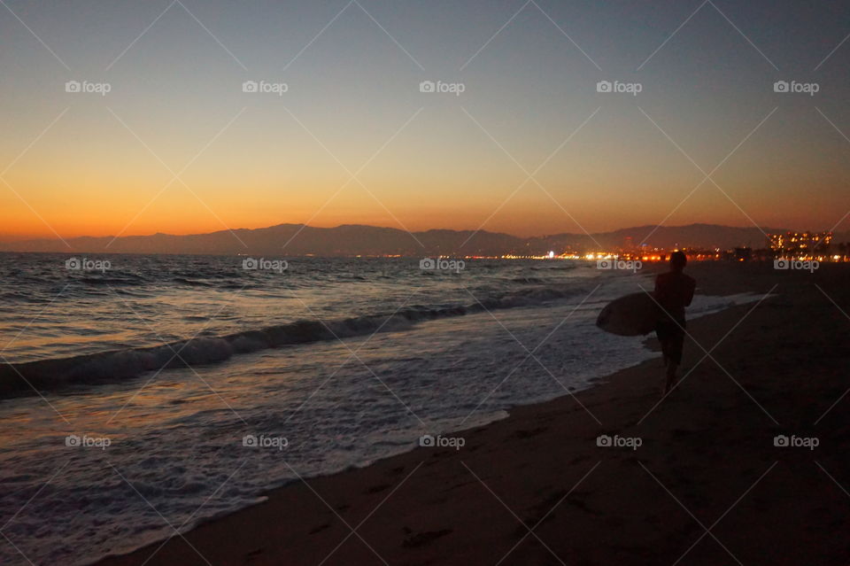 a surfer at the sunset in venice beach