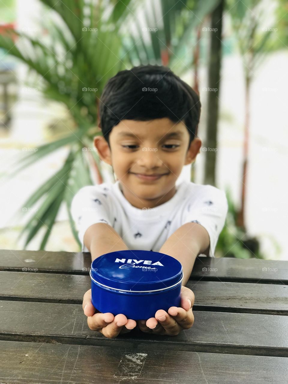 A boy with beautiful smile and Nivea cream in his hands.