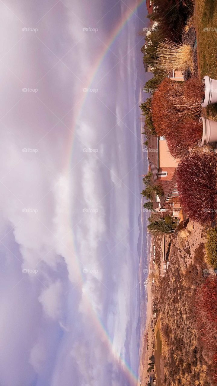 Full rainbow in residential neighborhood during a rainy winter day