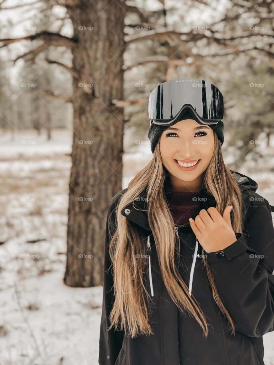 Young girl smiling while snowboarding in the snowy mountains.