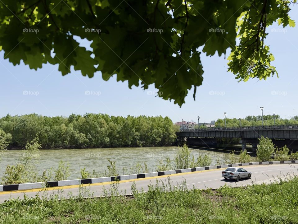 the car is driving along the embankment of the river