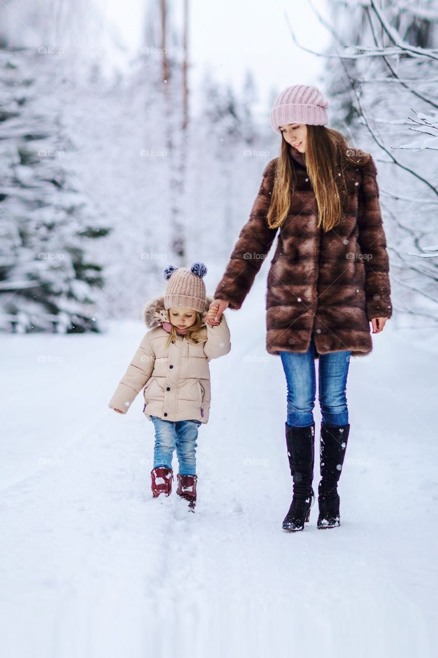 Mommy and daughter walking in winter park 