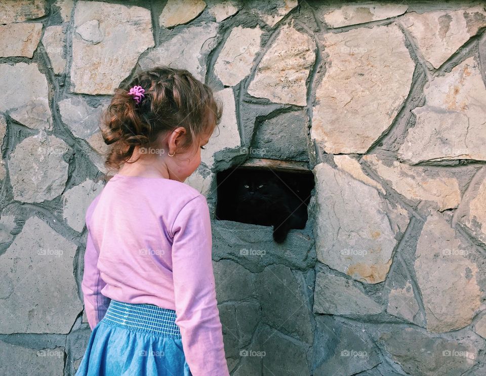 Cute girl finding cat in the wall.