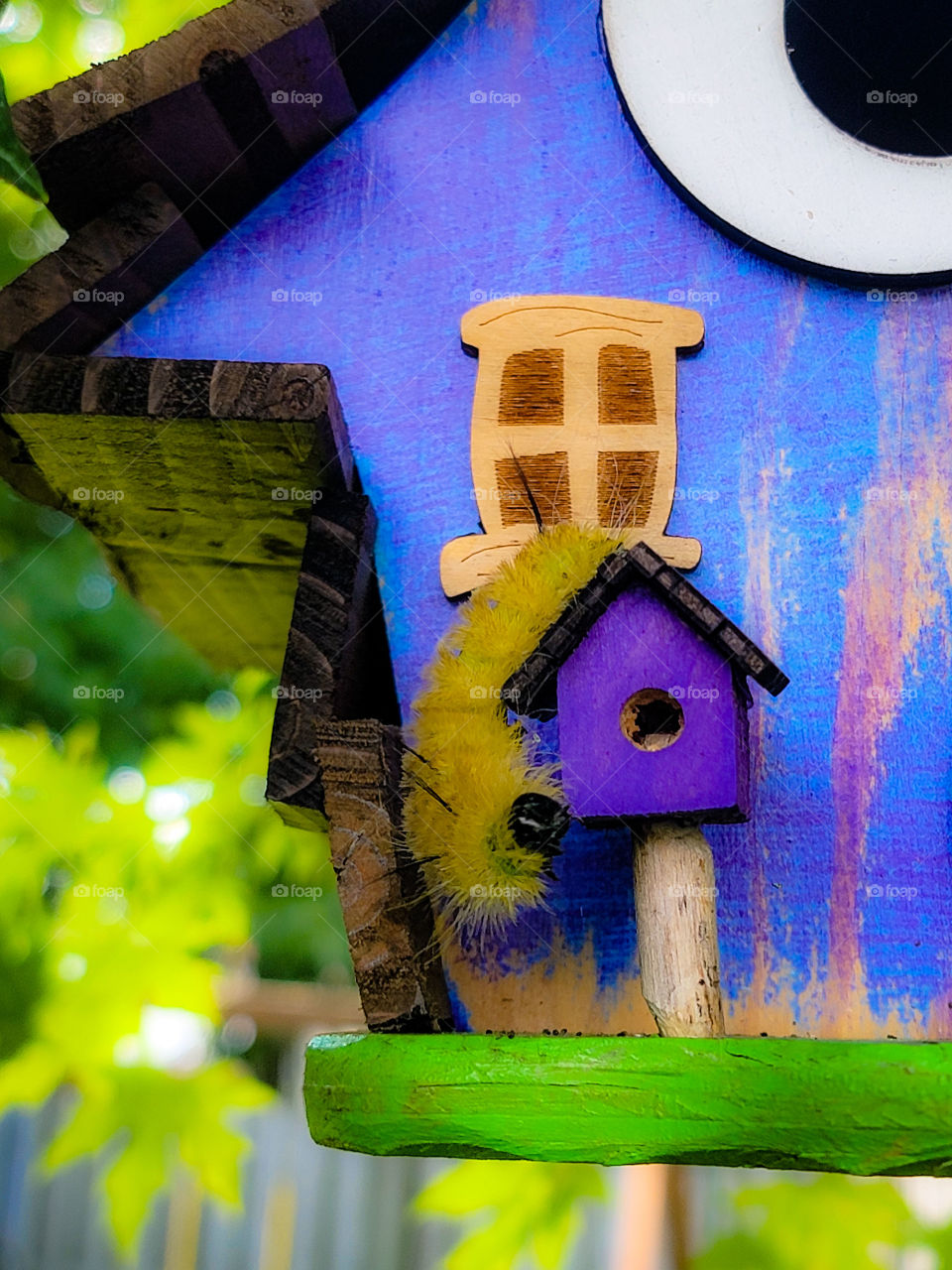 bright yellow and fuzzy caterpillar hanging out on a bright purple house.