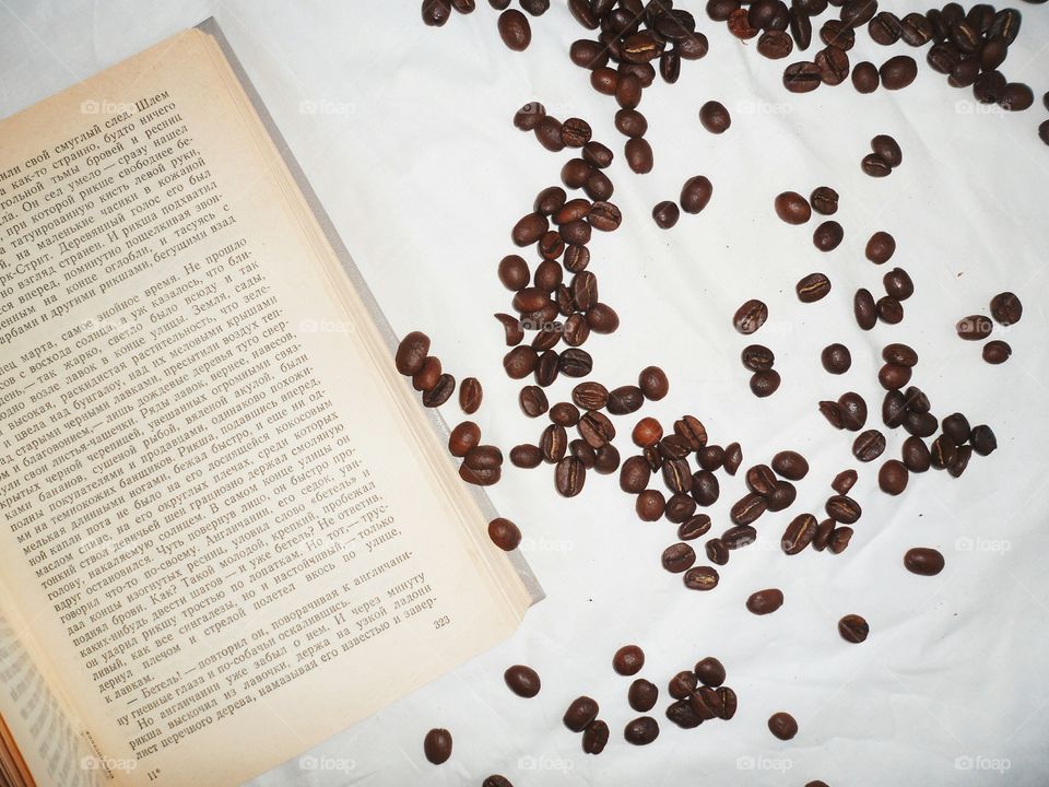 Open book and coffee beans on white background