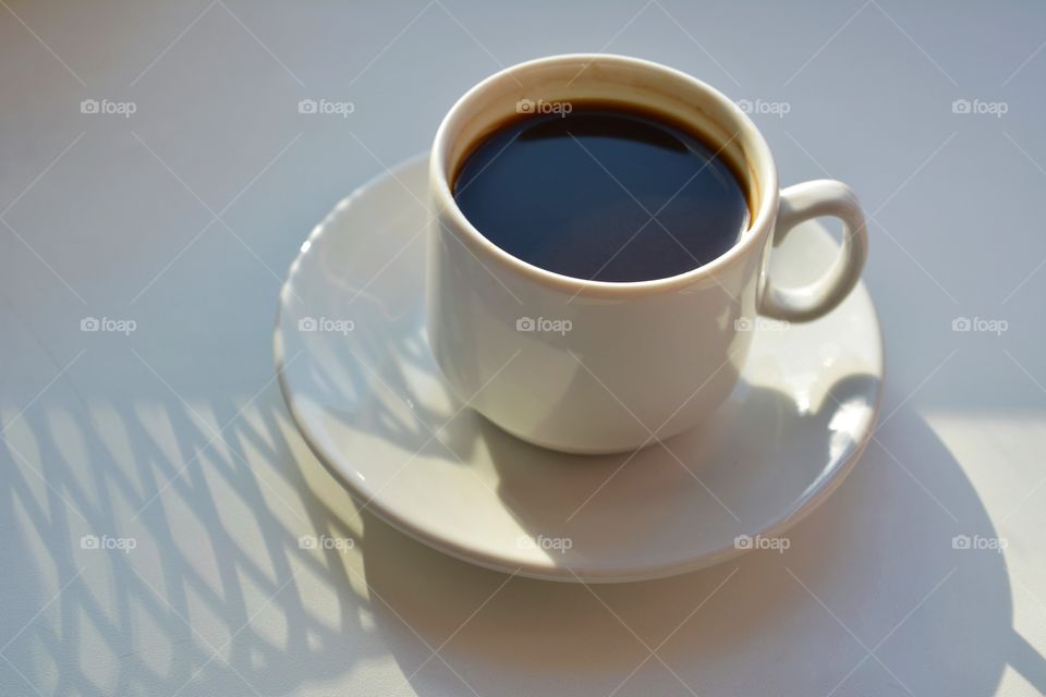 cup of coffee in sunlight and shadows on a white background, beautiful texture