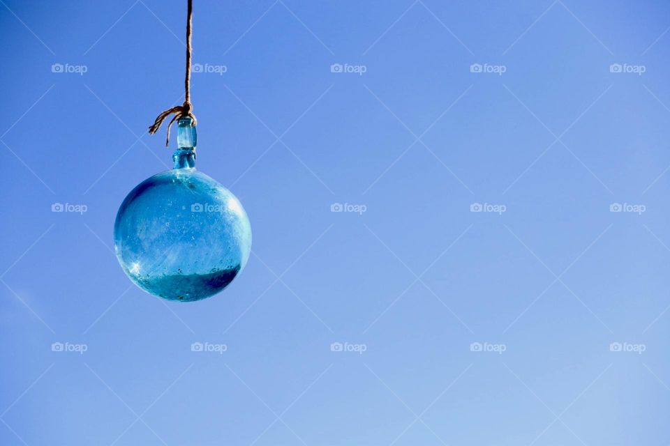 Blue glass ball hanging with blue sky on background 