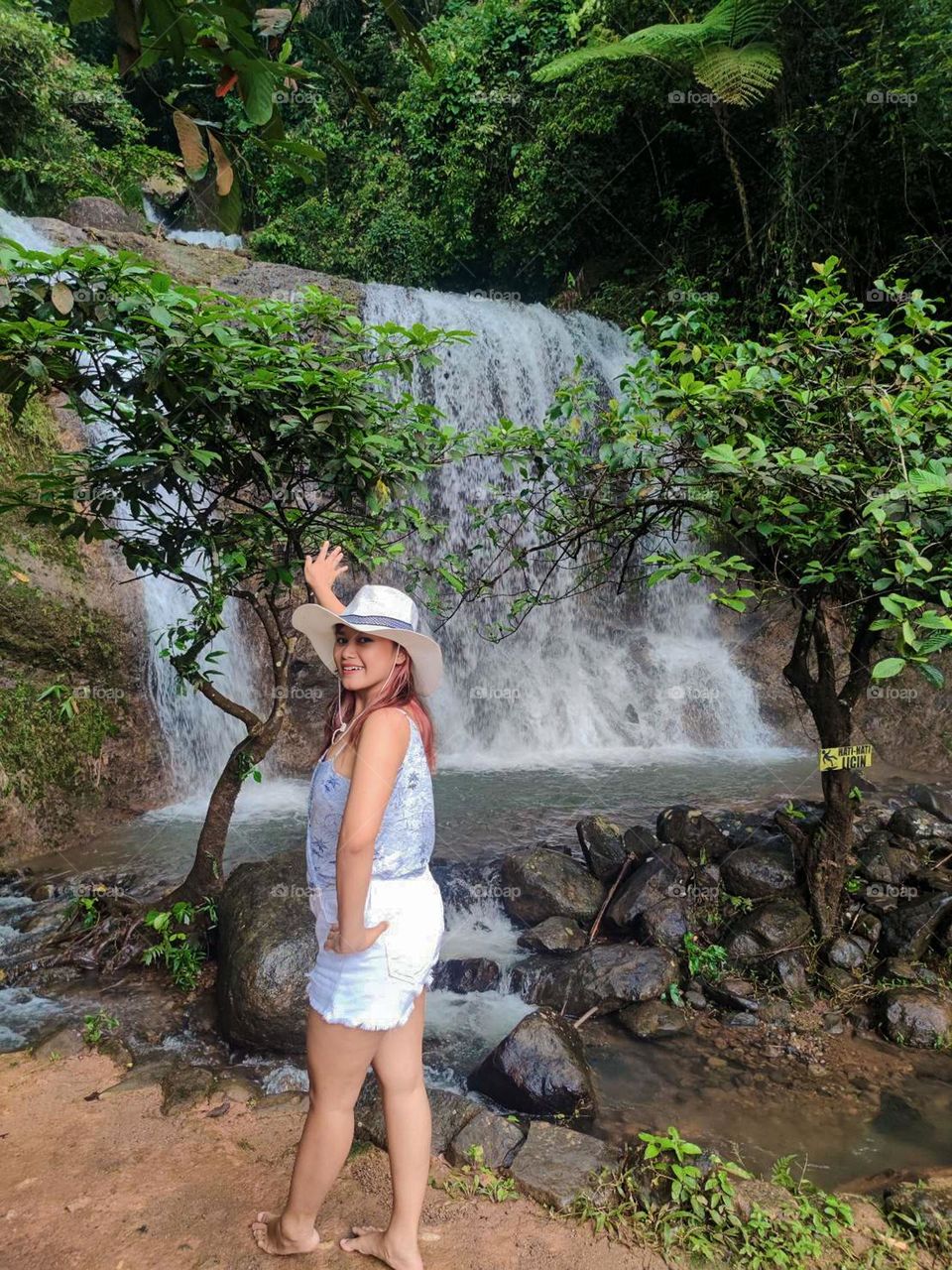 Portrait of woman standing against waterfall