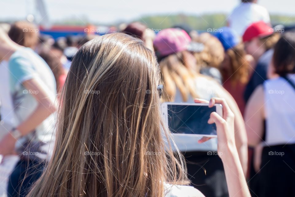 A girl taking a picture with her mobile phone of a concert crowd