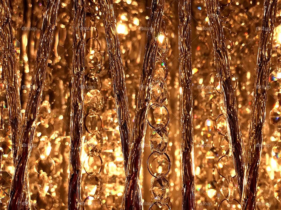 Golden crystal chandelier reflecting warm dazzling light rays.