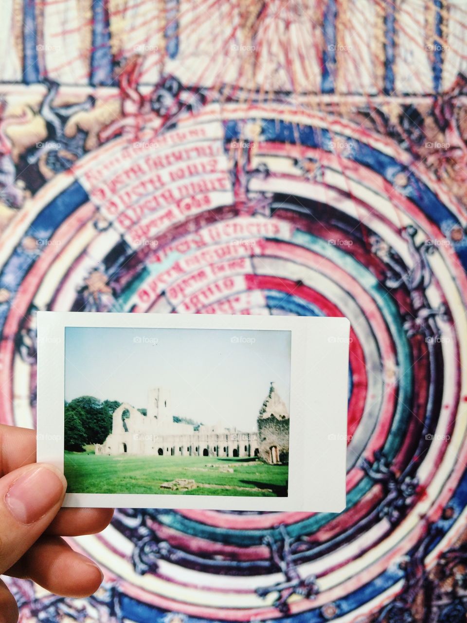 Hand holding polaroid photo of old building in England in front of art 