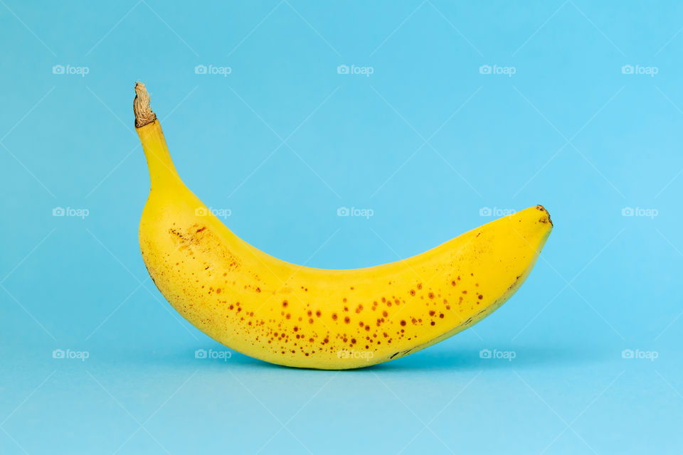 Single ripe banana on bright blue background