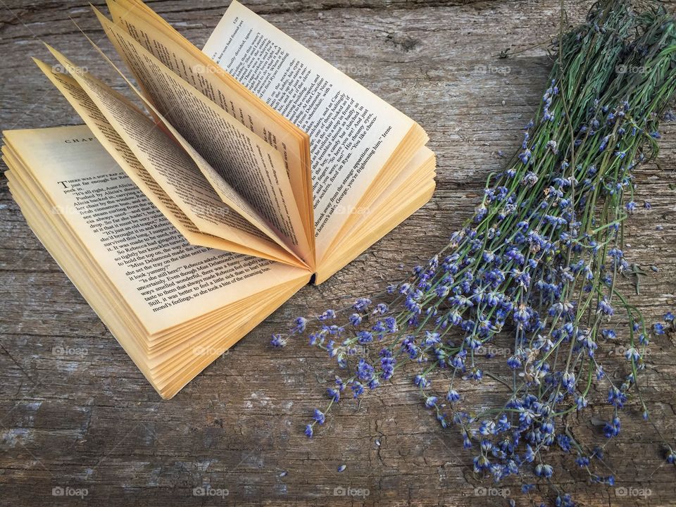 Open book with lavender on wooden table