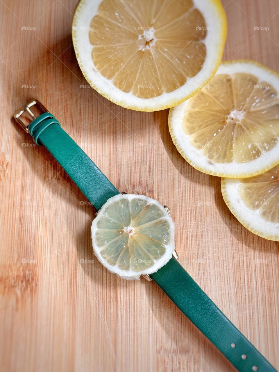 Watch with a green strap and a lemon on the dial, sliced ​​lemons lie next to it