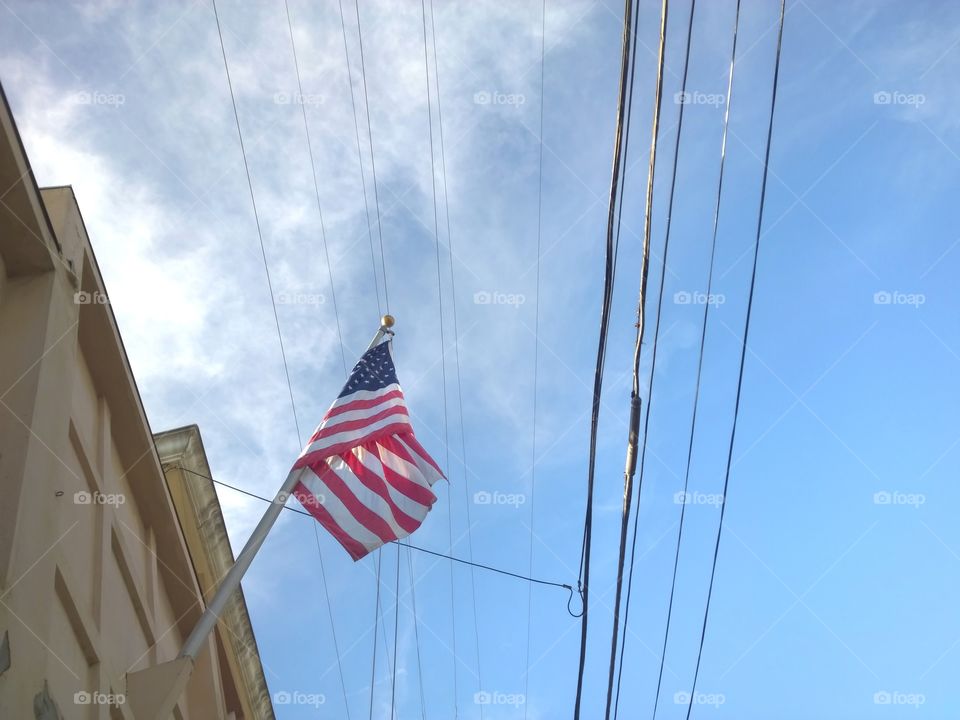 USA flags waving next to a building and telephone wires.