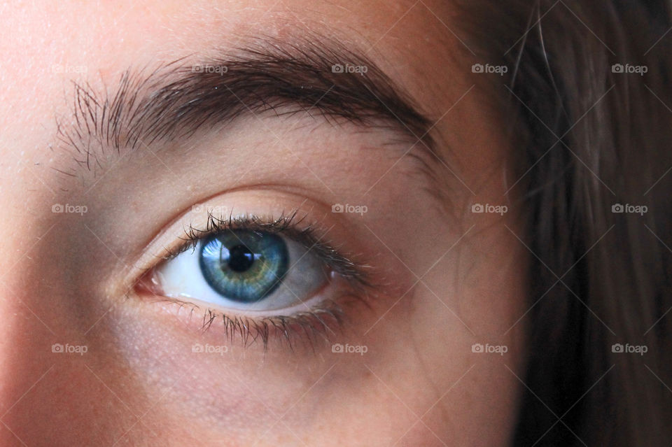 Closeup of one of my daughter’s big beautiful blue green eyes. The iris is rimmed with a deep blue and her dark lashes and brows make her eyes extraordinarily stunning.