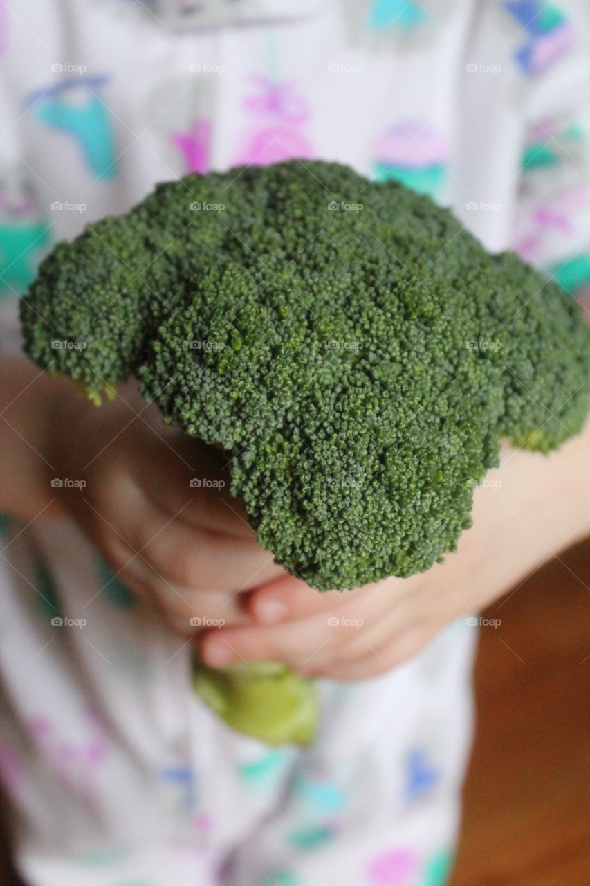 Mid section of girl holding broccoli