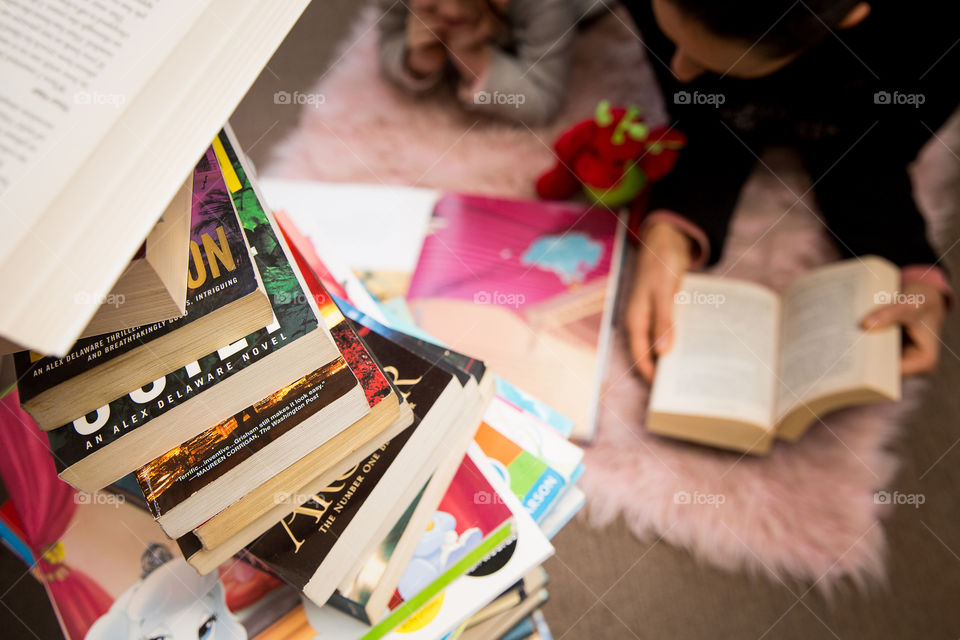 Mentally staying in shape, keeping the mind active by reading lots of different books. Mom and daughter reading together with a stack of books. Reading from a young age throughout your life to challenge the mind.