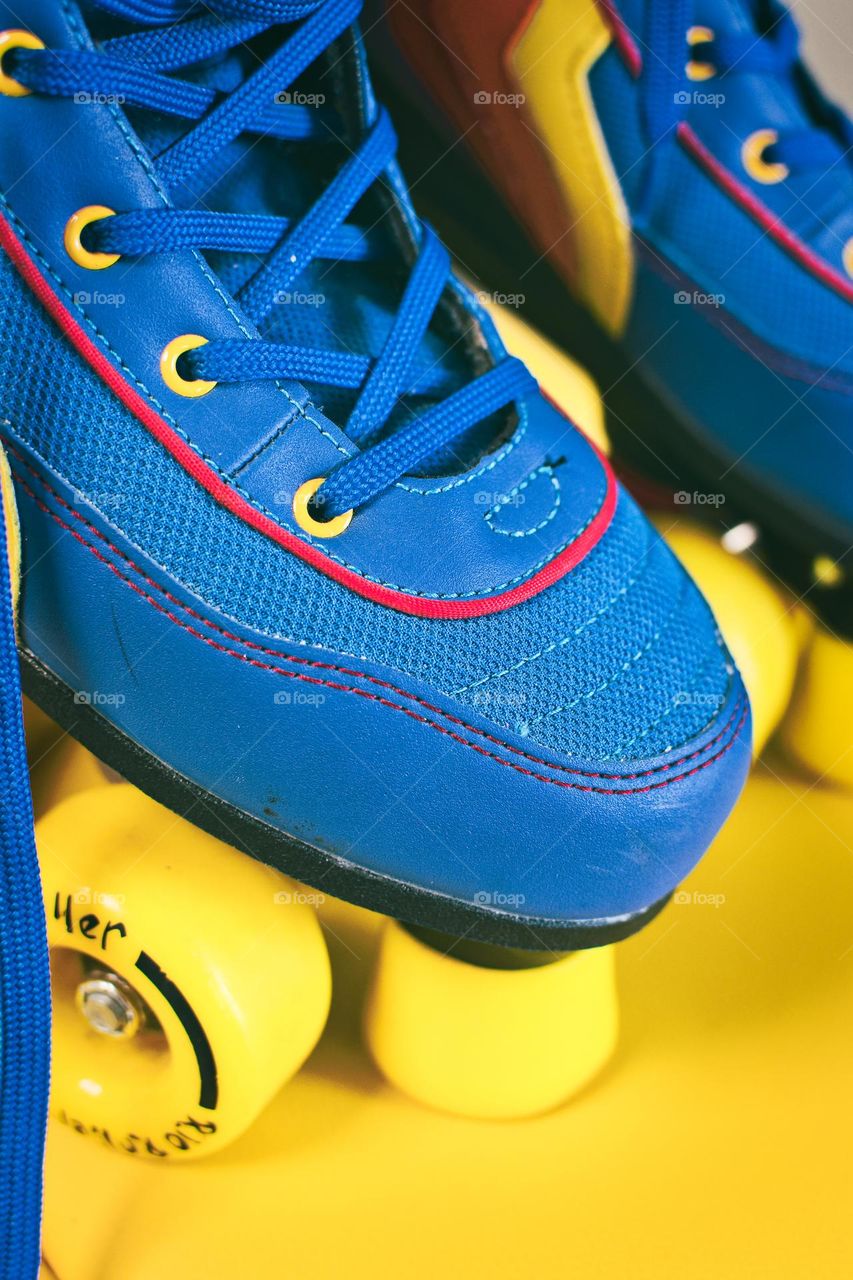 Blue roller skates with yellow wheels closeup