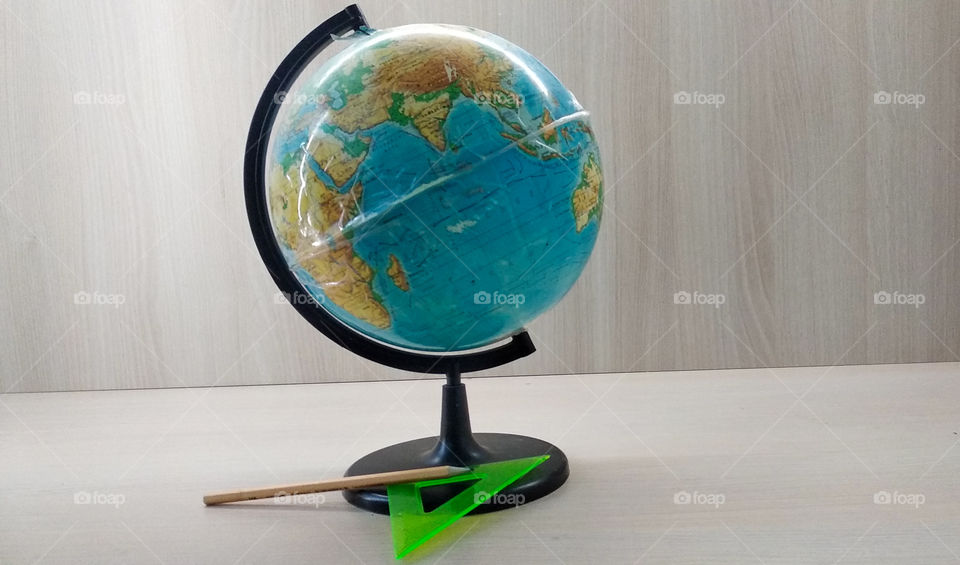 Globe with pencil and ruler are on the wood table