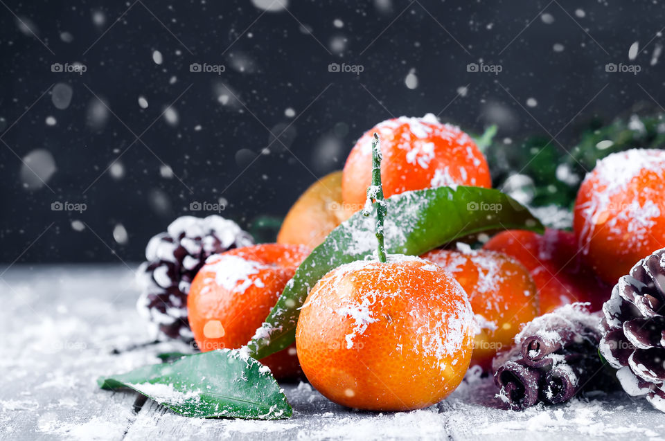 tangerines with snow on a dark wooden background