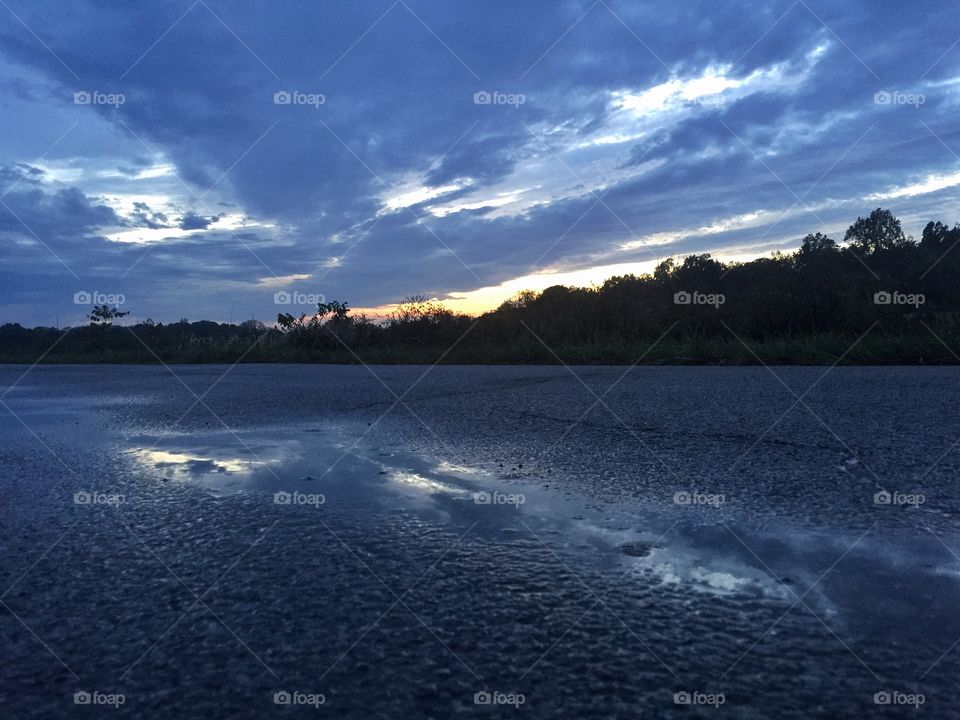 Reflections after the storms. . A low angle shot of a puddle reflecting a post-storm sunset. 