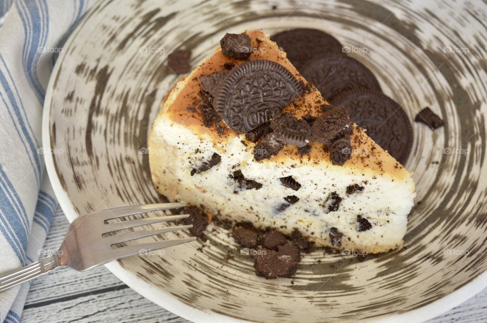 Oreo cookie cheesecake with Oreo cookies on a contrasting plate and a fork