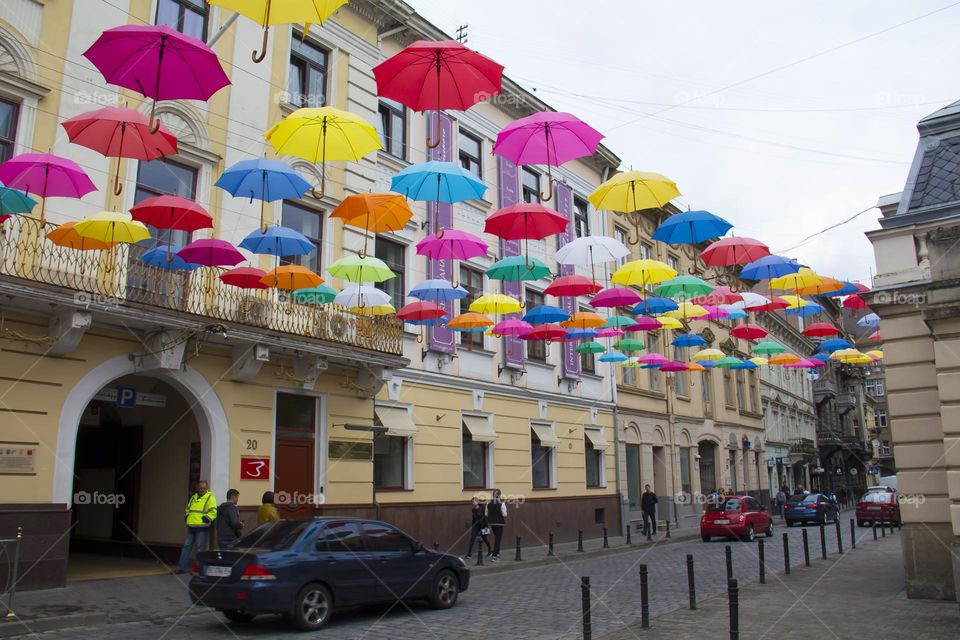 Multi-colored umbrellas hovering over a small, old town.